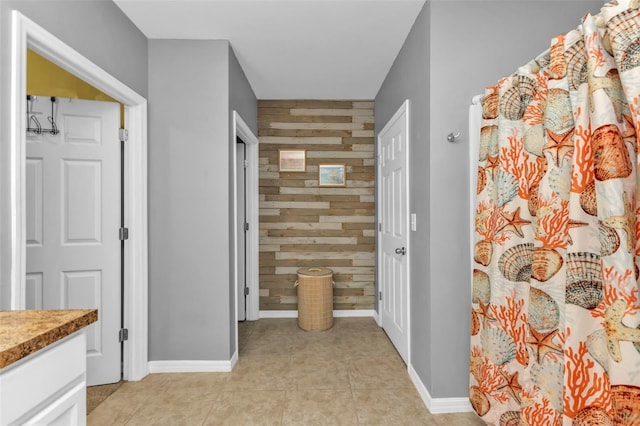 hallway featuring light tile patterned flooring and wood walls