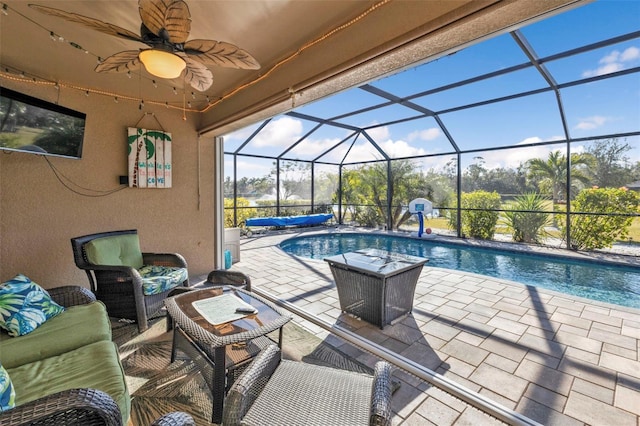 view of pool with glass enclosure, a patio area, outdoor lounge area, and ceiling fan