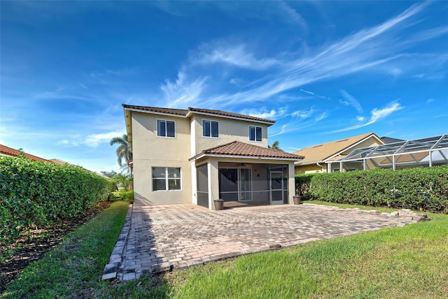 rear view of property with a yard, a patio area, and a sunroom