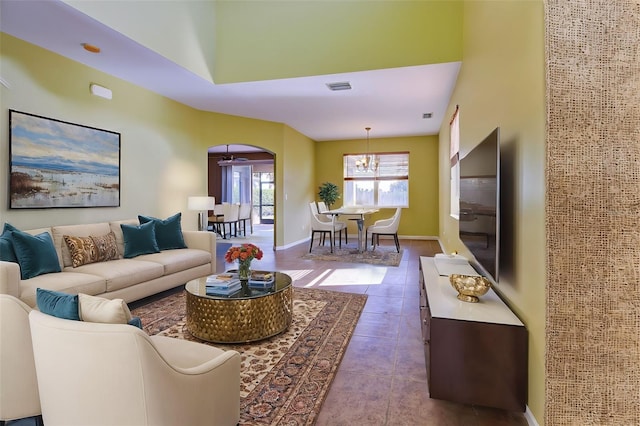 living room with light tile patterned floors, a towering ceiling, and a chandelier