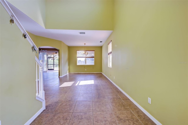 empty room featuring light tile patterned flooring and a chandelier