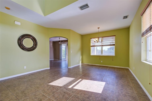 empty room with dark tile patterned floors and a chandelier