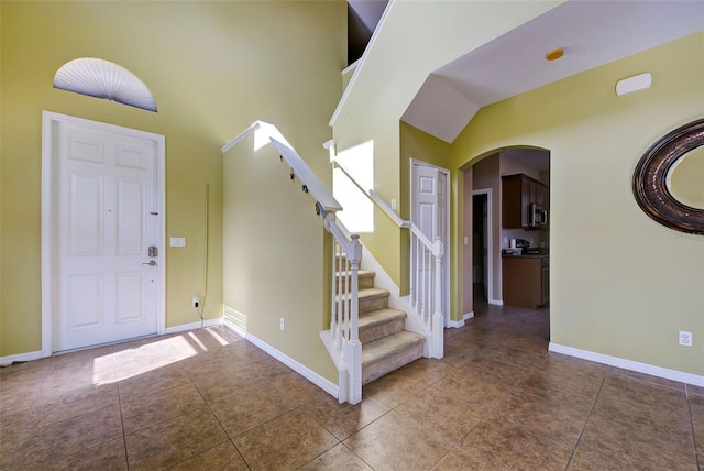 foyer entrance with tile patterned flooring and high vaulted ceiling