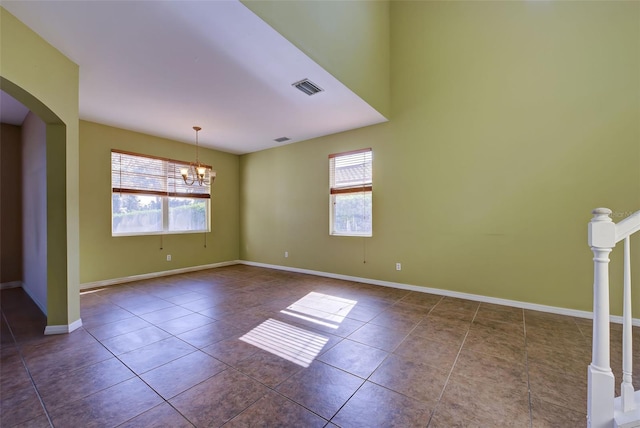 spare room featuring dark tile patterned flooring and an inviting chandelier