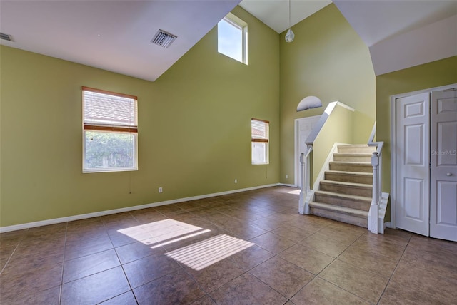 unfurnished living room featuring a towering ceiling, tile patterned floors, and plenty of natural light