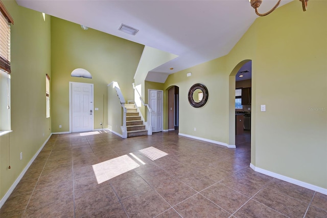 entryway with tile patterned flooring, a healthy amount of sunlight, and a high ceiling