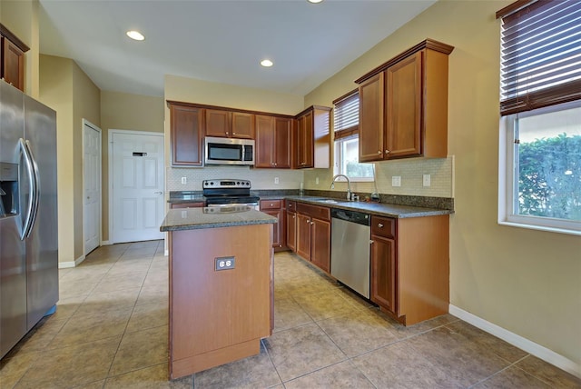 kitchen featuring sink, a center island, light tile patterned floors, and appliances with stainless steel finishes