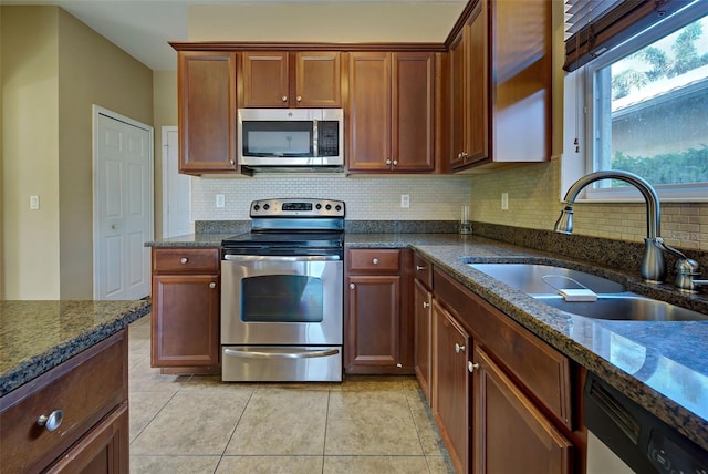 kitchen with backsplash, sink, dark stone counters, and appliances with stainless steel finishes