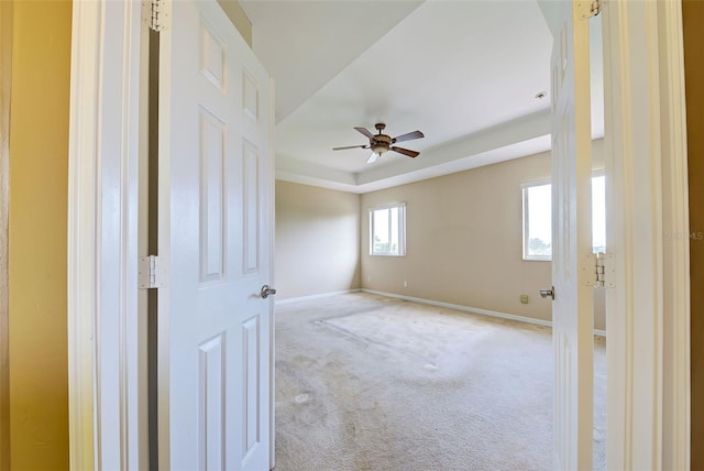 carpeted empty room with a tray ceiling and ceiling fan