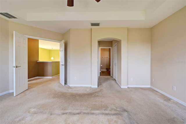 unfurnished bedroom featuring light colored carpet, ceiling fan, and a tray ceiling