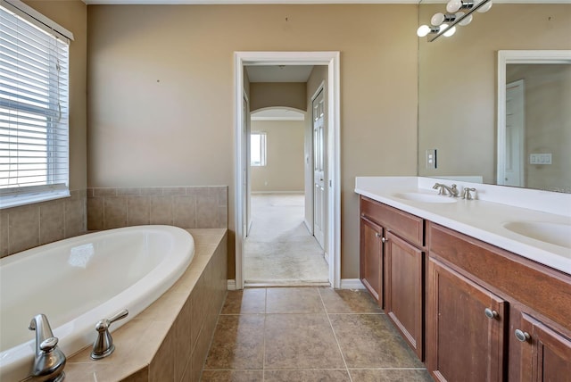 bathroom with tiled tub, tile patterned flooring, and vanity