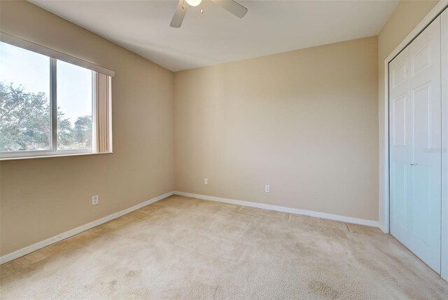 unfurnished bedroom with ceiling fan, light colored carpet, and a closet