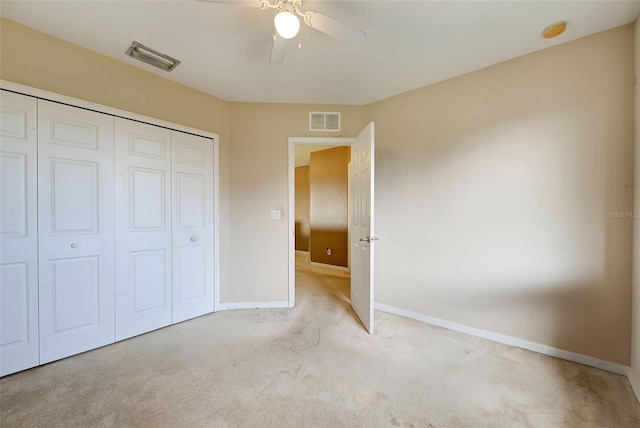 unfurnished bedroom featuring ceiling fan, light colored carpet, and a closet