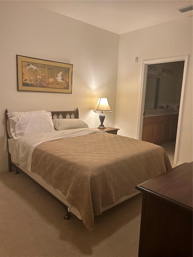 bedroom with ensuite bathroom and carpet floors