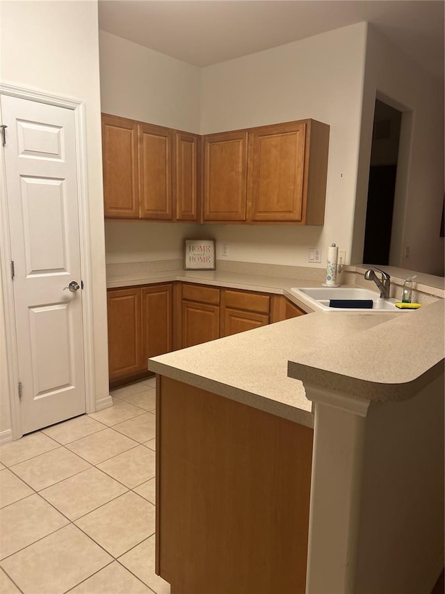 kitchen featuring light countertops, light tile patterned flooring, a sink, and a peninsula