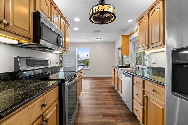 kitchen featuring hanging light fixtures, stainless steel appliances, dark hardwood / wood-style floors, dark stone countertops, and a textured ceiling