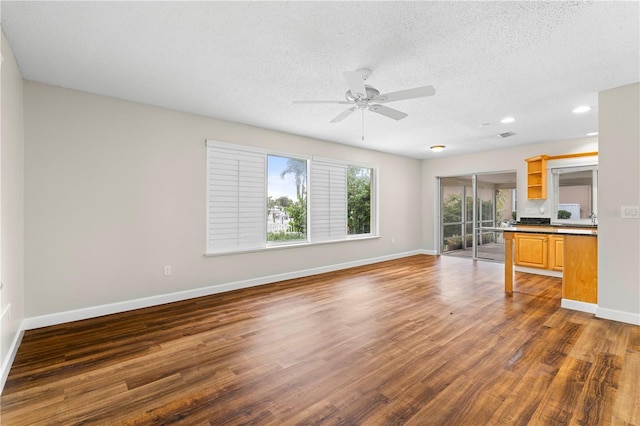 unfurnished living room with ceiling fan, dark hardwood / wood-style flooring, and a textured ceiling