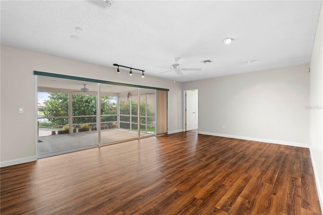 empty room with ceiling fan, dark hardwood / wood-style flooring, a textured ceiling, and track lighting