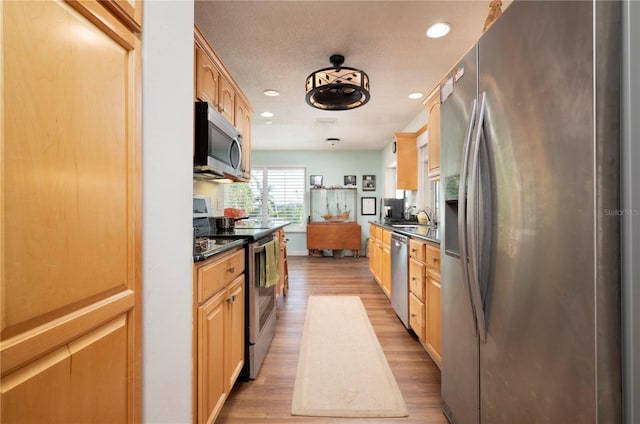 kitchen featuring light brown cabinets, sink, light hardwood / wood-style flooring, a textured ceiling, and appliances with stainless steel finishes