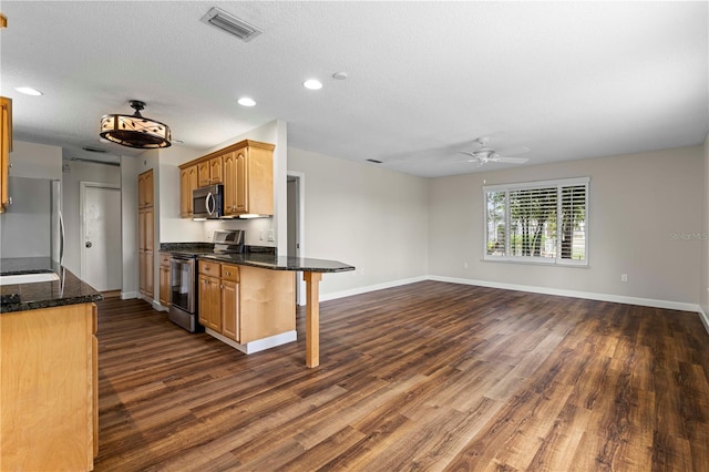 kitchen featuring a kitchen breakfast bar, a textured ceiling, stainless steel appliances, ceiling fan, and dark hardwood / wood-style floors