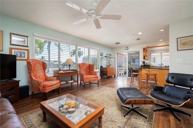 living room featuring hardwood / wood-style floors, ceiling fan, sink, and a textured ceiling