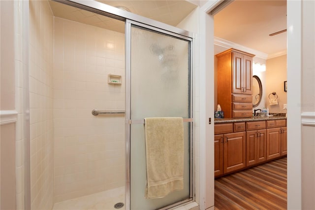 bathroom featuring vanity, hardwood / wood-style flooring, walk in shower, and ornamental molding