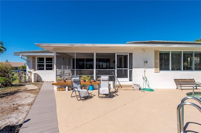 back of property with a sunroom and a patio area