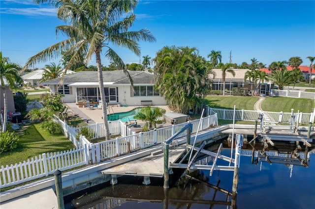 view of dock with a fenced in pool, a yard, a water view, and a patio