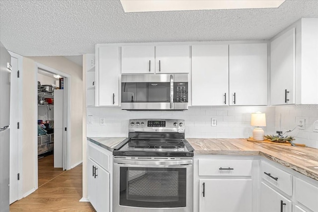 kitchen with white cabinets, light hardwood / wood-style flooring, a textured ceiling, appliances with stainless steel finishes, and tasteful backsplash