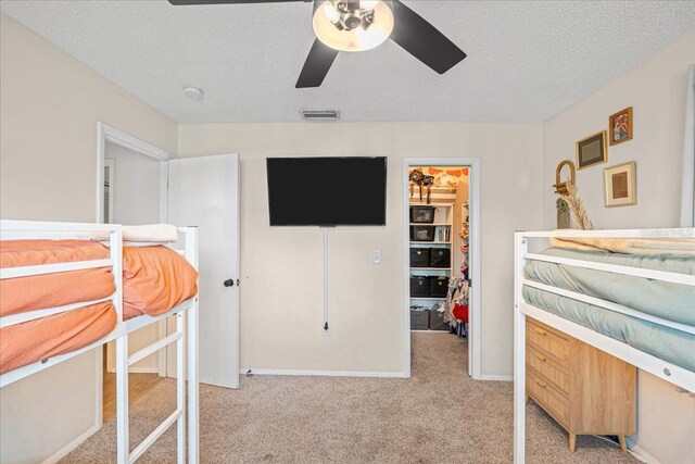 carpeted bedroom with a closet, a spacious closet, visible vents, and a textured ceiling