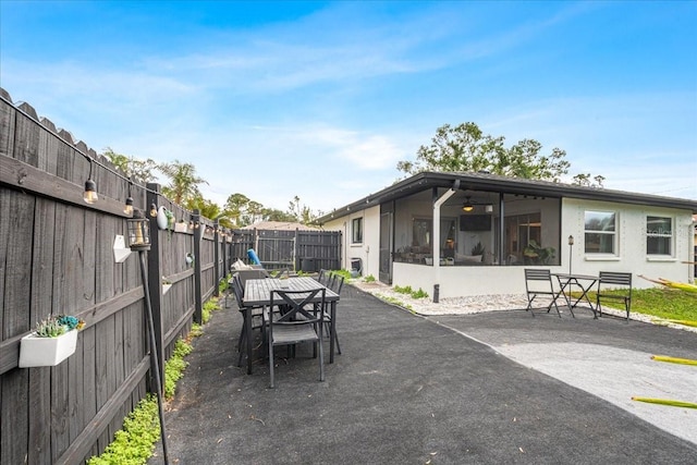 view of patio featuring outdoor dining area, a fenced backyard, and a sunroom