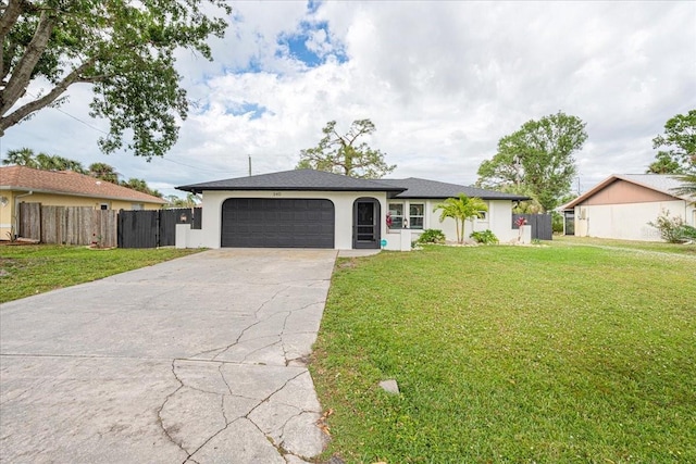 ranch-style house featuring an attached garage, driveway, fence, and a front yard