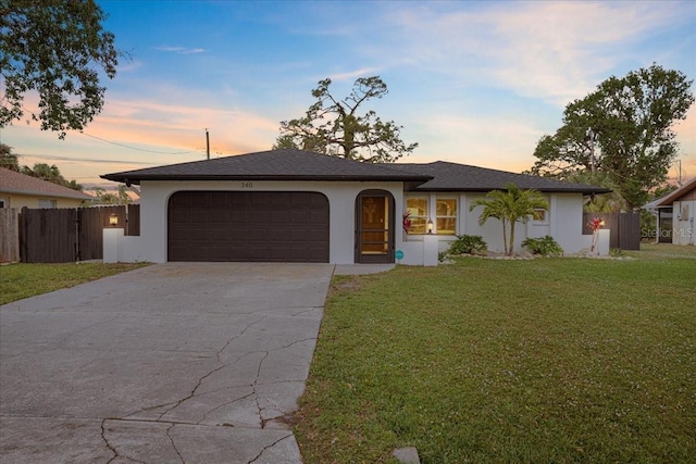 ranch-style home with driveway, an attached garage, fence, and a lawn