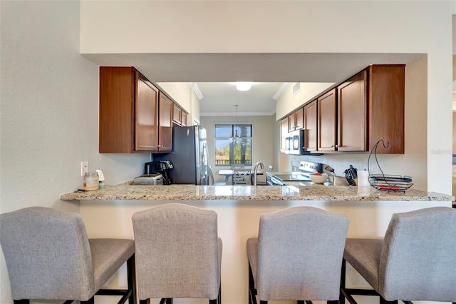 kitchen with kitchen peninsula, stainless steel appliances, light stone countertops, and ornamental molding