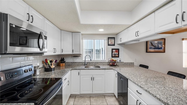 kitchen with black appliances, white cabinets, sink, light stone countertops, and light tile patterned floors