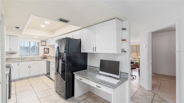 kitchen featuring light stone counters, black refrigerator with ice dispenser, sink, light tile patterned floors, and white cabinets