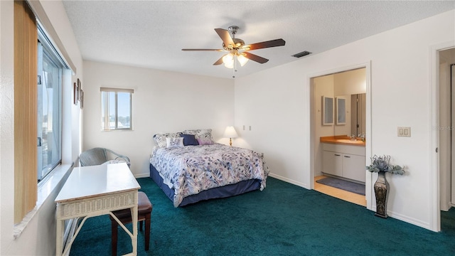 bedroom with connected bathroom, ceiling fan, sink, dark colored carpet, and a textured ceiling