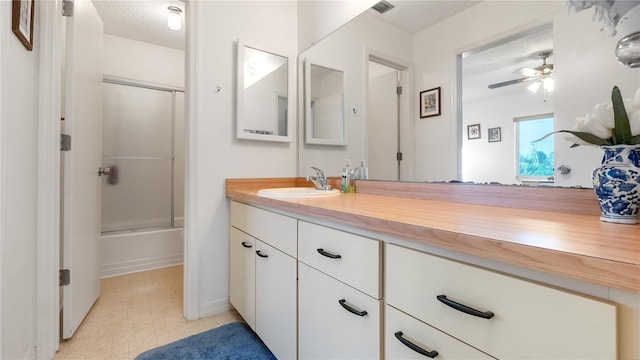 bathroom with vanity, a textured ceiling, combined bath / shower with glass door, and ceiling fan