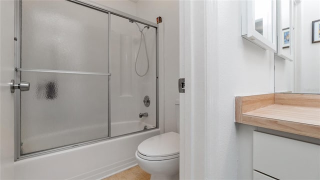 bathroom featuring toilet and shower / bath combination with glass door