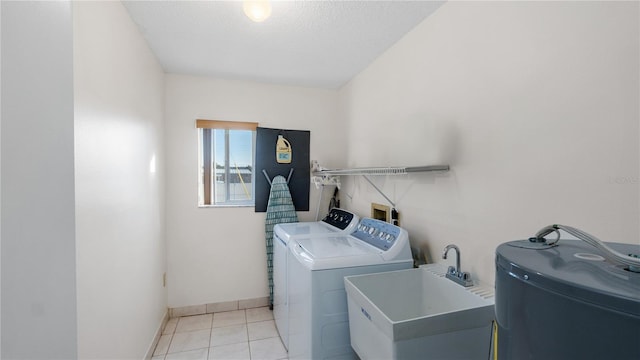 washroom with electric water heater, a textured ceiling, sink, light tile patterned floors, and washing machine and dryer