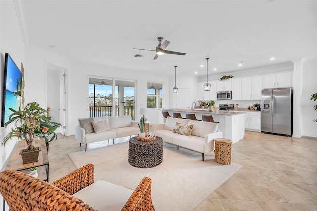 living room with ceiling fan, sink, crown molding, and light tile patterned flooring