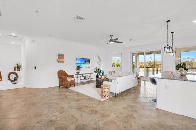 tiled living room featuring crown molding and ceiling fan with notable chandelier