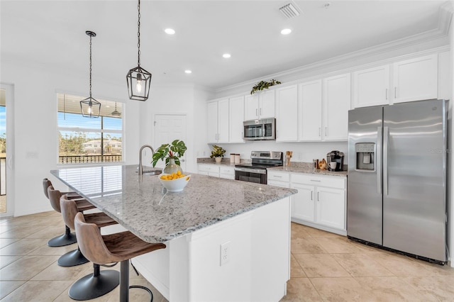 kitchen with white cabinets, light stone countertops, stainless steel appliances, and a center island with sink