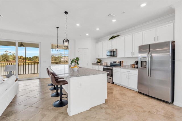 kitchen with a center island with sink, hanging light fixtures, light stone countertops, appliances with stainless steel finishes, and white cabinets