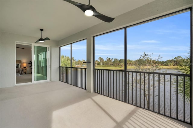 unfurnished sunroom featuring ceiling fan and a water view