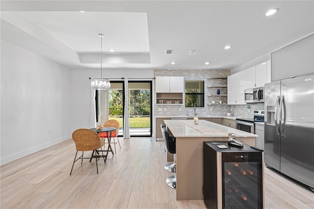 kitchen featuring pendant lighting, white cabinets, a kitchen island, stainless steel appliances, and beverage cooler