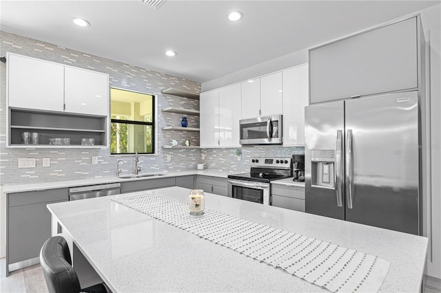 kitchen with tasteful backsplash, light stone countertops, sink, and appliances with stainless steel finishes