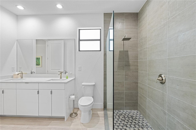 bathroom with a tile shower, vanity, and toilet