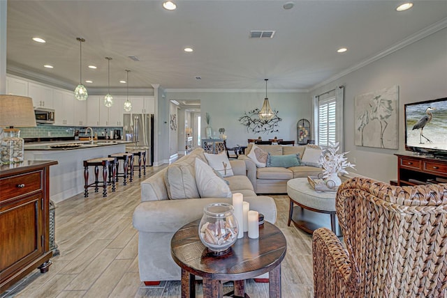 living room featuring sink, crown molding, and light hardwood / wood-style flooring