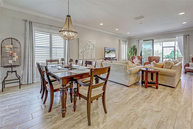 dining space with light hardwood / wood-style flooring, crown molding, and an inviting chandelier